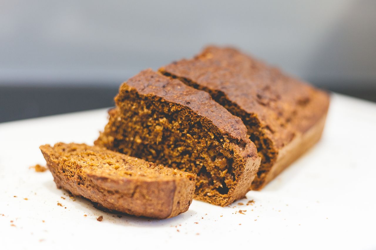 Home Delicious homemade banana bread sliced on a white surface with a rustic texture.